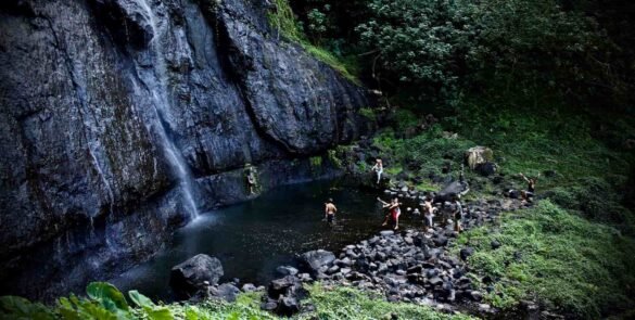 Activité en famille à Moorea - Vue aérienne d'une famille se baignant dans une cascade lors d'une excursion.