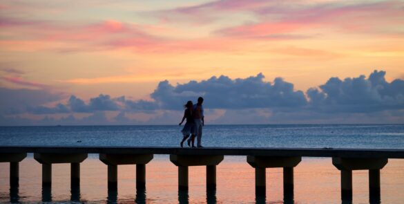 Hôtel Kia Ora Resort & Spa 4* à Rangiroa - couple marchant sur le ponton de l'hôtel au coucher du soleil.