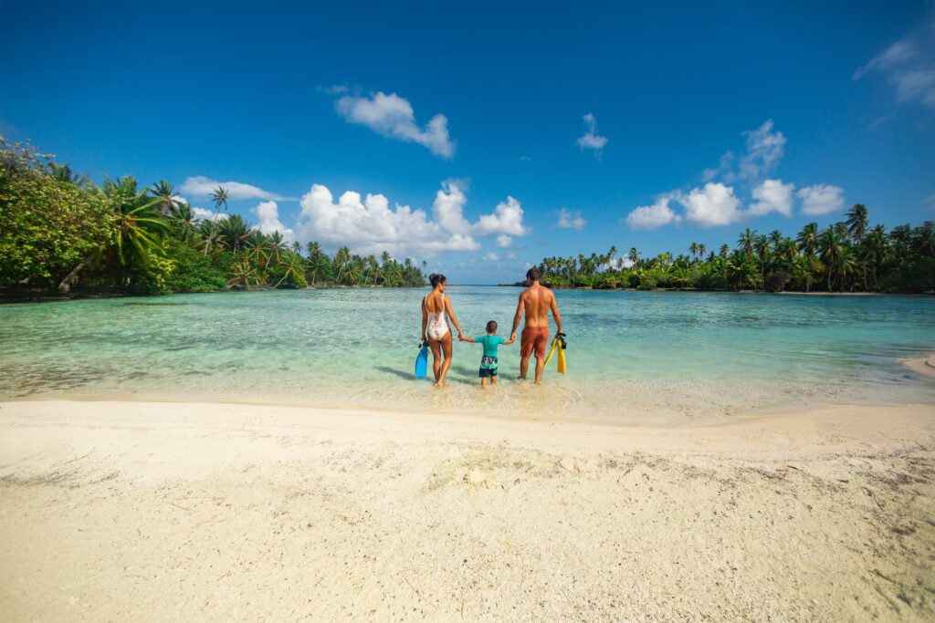 couple tenant leur enfant par la main et marchant dans le lagon de Taha'a