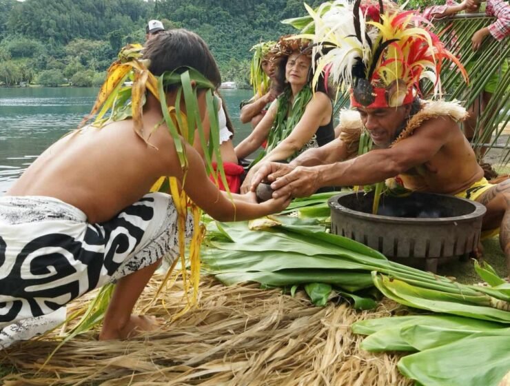 couple avec un enfant assis sur la plage, en costume traditionnel polynésien - Écotourisme en Polynésie : à la découverte de la nature préservée.