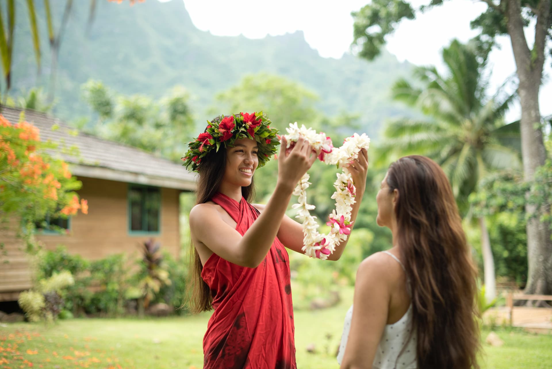 jeune femme polynésienne avec une couronne de fleurs mettant un collier de fleurs de bienvenue à une touriste