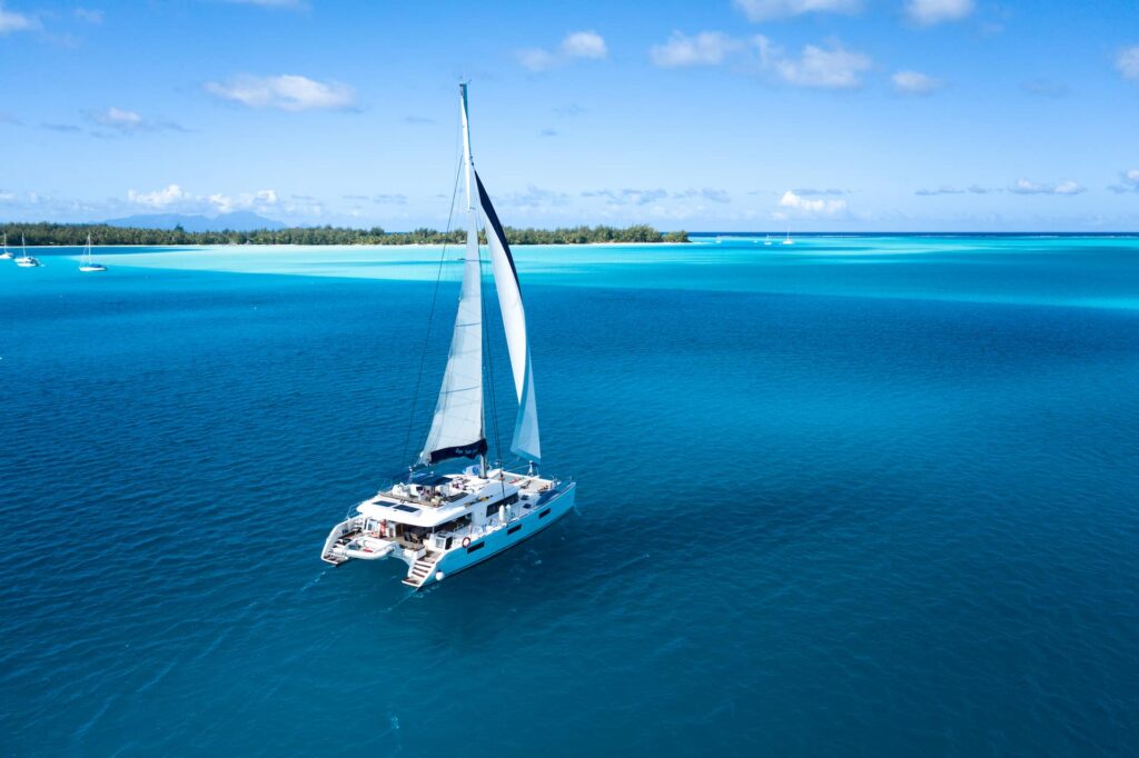 Croisière Dream Yacht Charter. Vue aérienne sur un catamaran Lagoon 620. Lagon et motu en arrière plan.