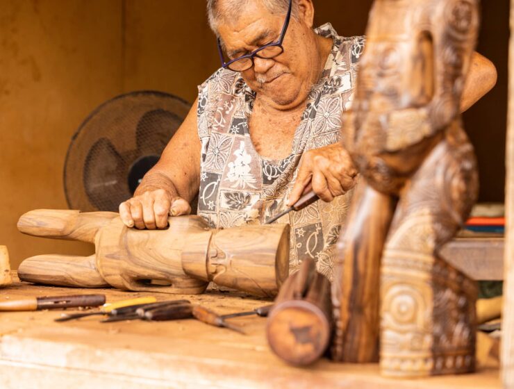 Polynésien sculptant un tiki dans un morceau de bois