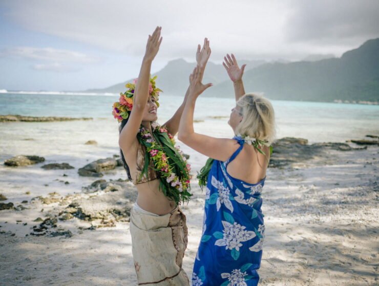 femme polynésienne apprenant la danse tahitienne à une touriste sur la plage au coucher du soleil - slow travel