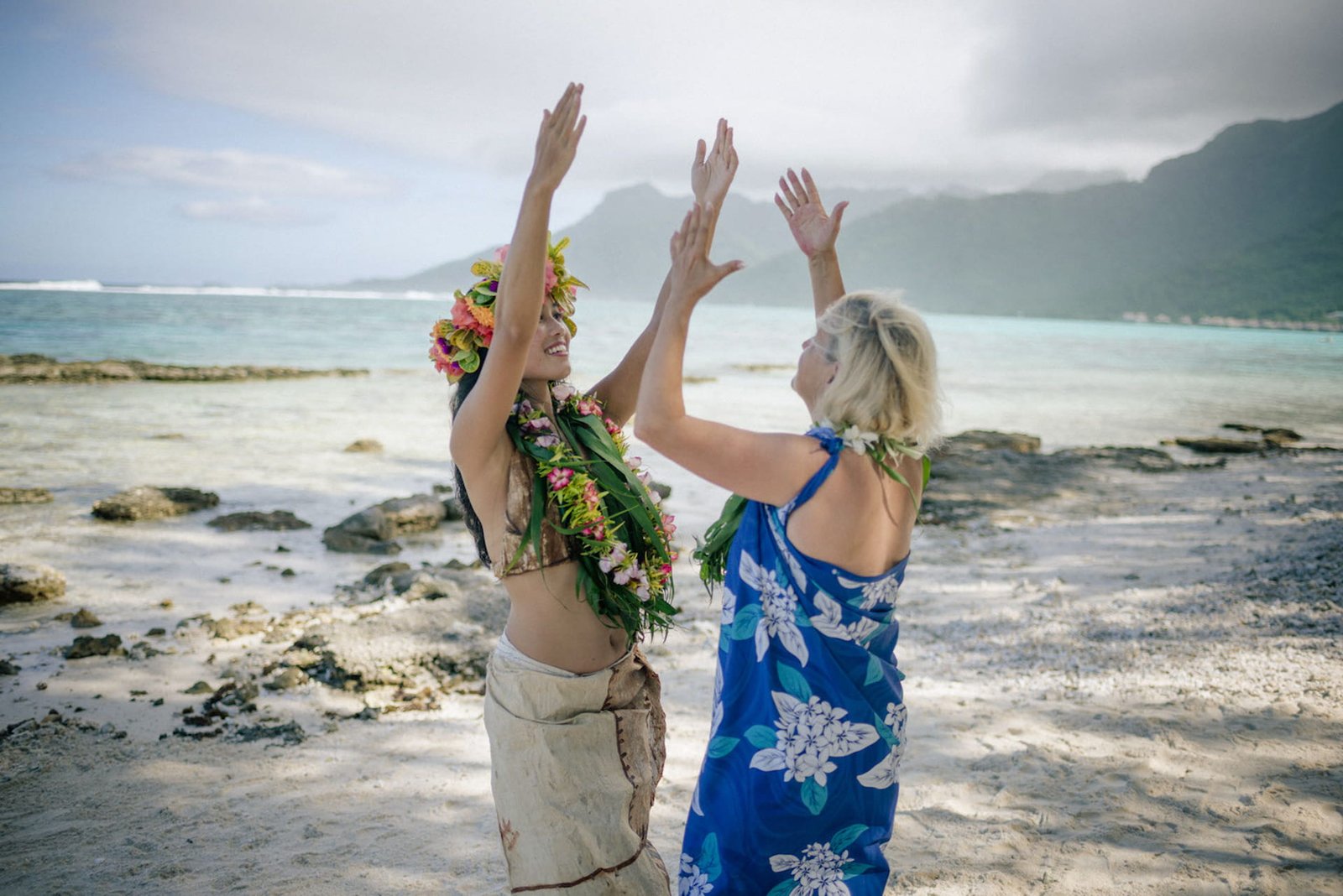 femme polynésienne apprenant la danse tahitienne à une touriste sur la plage au coucher du soleil - slow travel