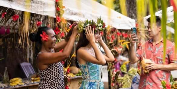 femme polynésienne ajustant une couronnes de fleurs sur la tête d'une touriste