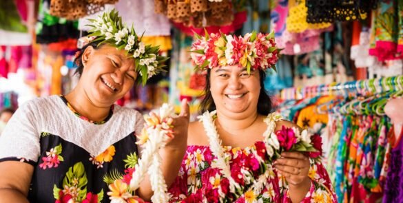deux femmes polynésiennes portant des couronnes de fleurs sur la tête et des colliers dans les mains au marché local de Papeete