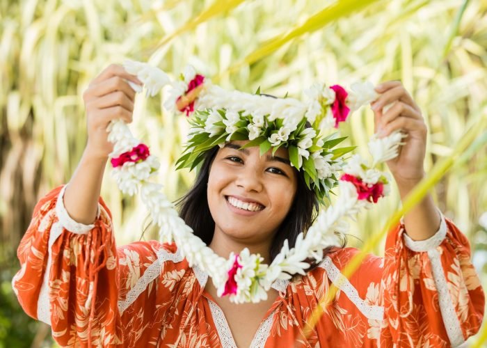 femme polynésienne en tenue local approchant un collier de fleurs pour la bienvenue