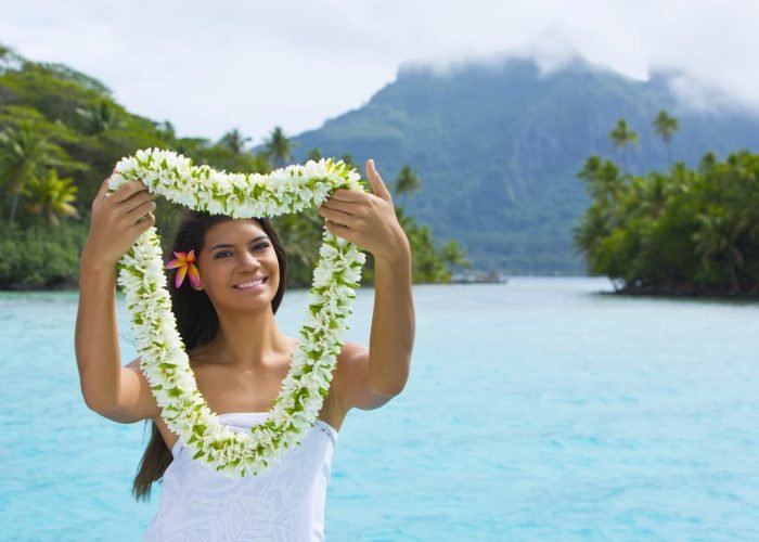 Femme polynésienne à Bora Bora portant collier de fleurs de Tiare pour souhaiter la bienvenue.