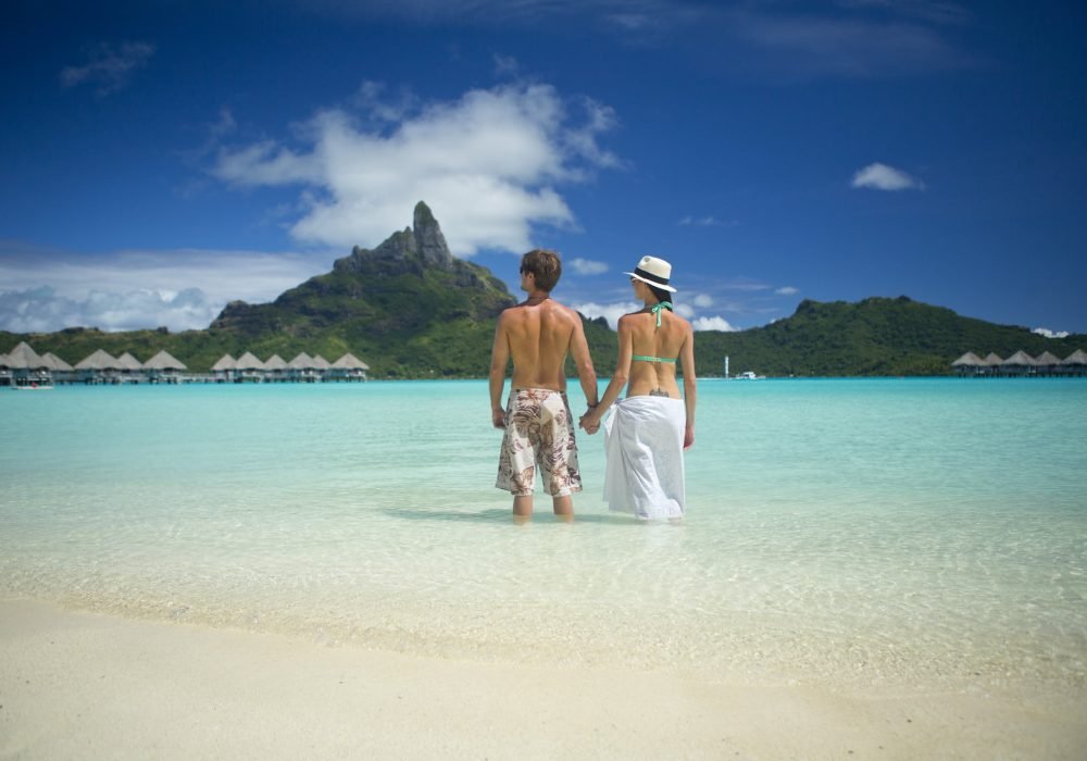 couple se tenant la main dans le lagon face au mont Otemanu à Bora Bora - voyage de noces