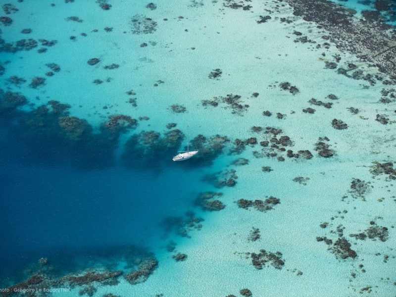 Vue aérienne vue le lagon de Bora Bora. Patates de corail, récif tombant et voilier.