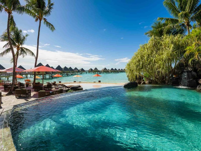 Hôtel Intercontinental Moana Bora Bora 4*. Vue sur la piscine et le bar Vini Vini. Bungalows sur Pilotis et lagon en arrière plan