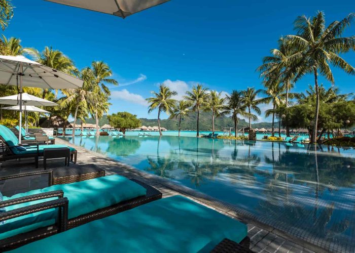 Hôtel Intercontinental Bora Bora Thalasso & Spa 5* - vue sur la piscine, les cocotier et le lagon avec des villas sur pilotis en arrière plan