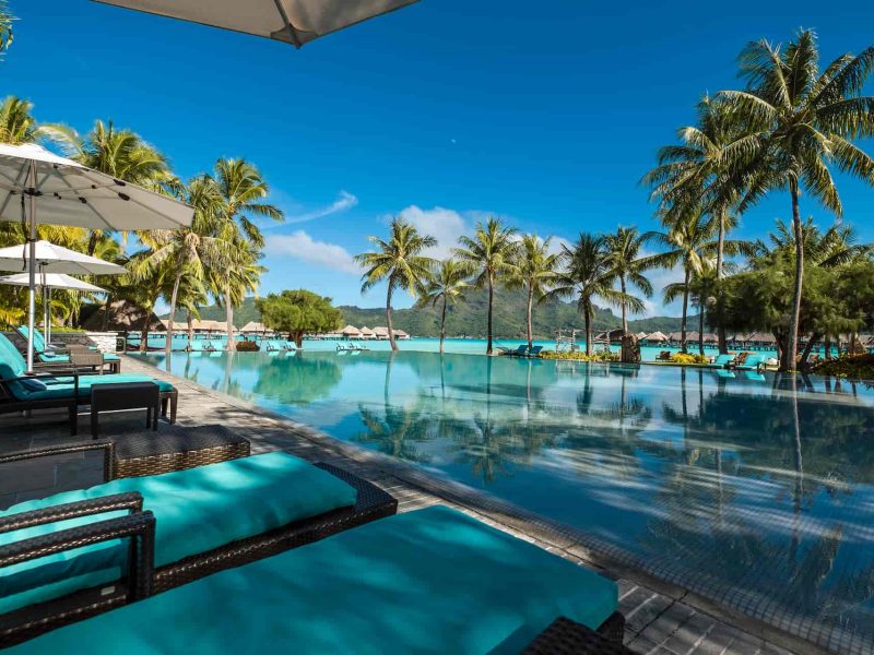 Hôtel Intercontinental Bora Bora Thalasso & Spa 5* - vue sur la piscine, les cocotier et le lagon avec des villas sur pilotis en arrière plan