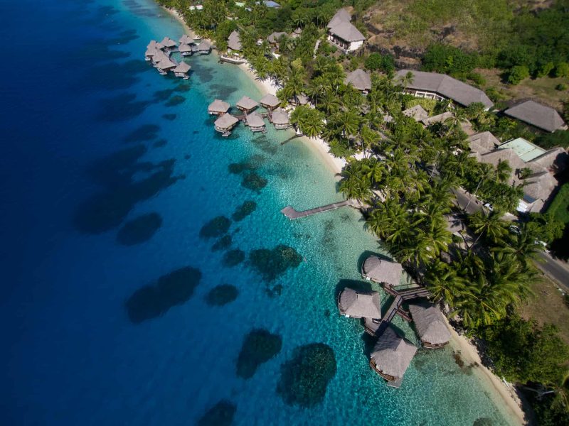 Hôtel Maitai Polynesia 3* à Bora Bora. Vue aérienne sur le lagon, les patates de corail et les bungalows sur pilotis. Vue sur les cocotiers et les installations de l'hôtel.