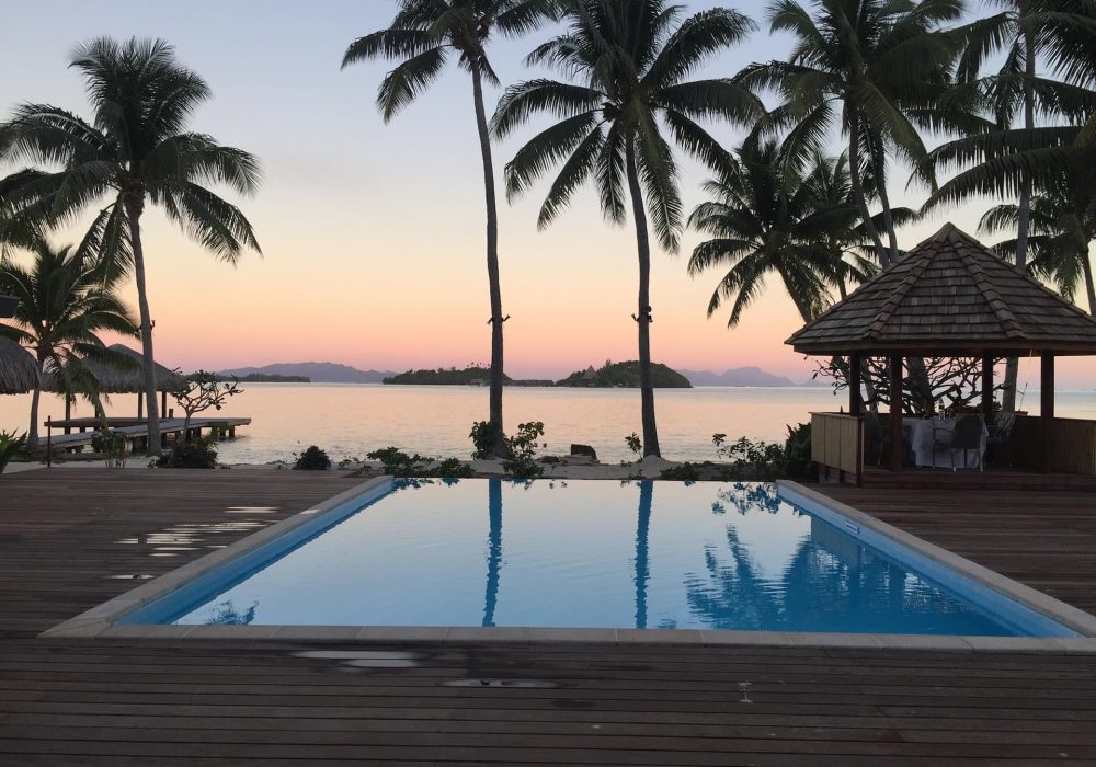 vue piscine, palmiers et lagon au coucher du soleil depuis l'hôtel Royal Bora Bora 3*** à Bora Bora