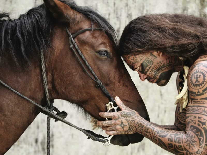 homme marquisien tatoué tenant la tete d'un cheval, tout deux de profil