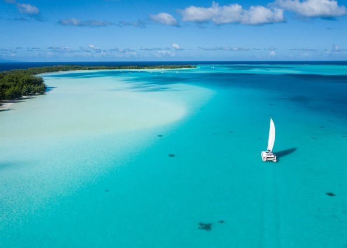 Vue aérienne d'un catamaran Lagoon 620 sur un lagon turquoise - Croisières en Polynésie française