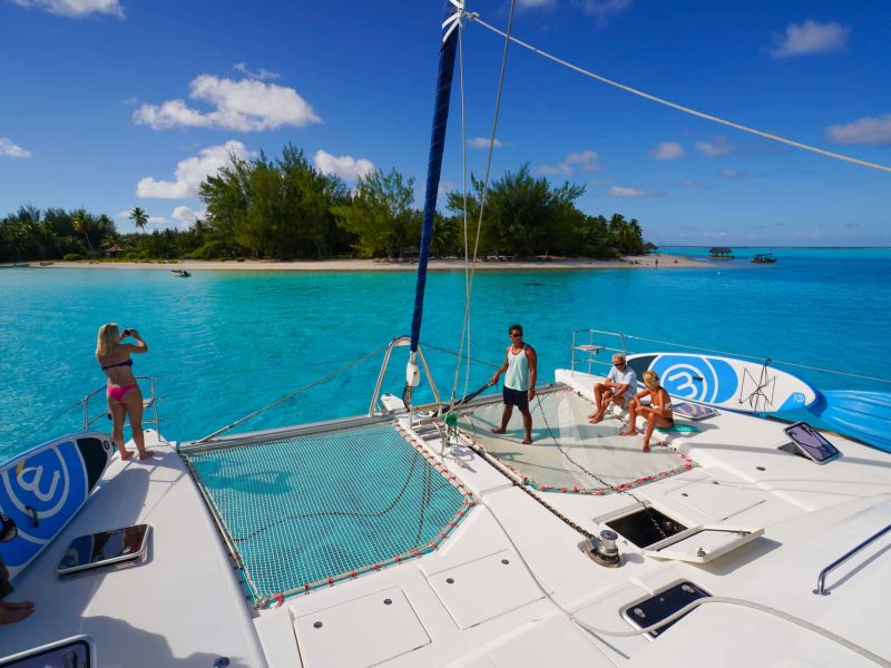 Croisière Dream Yacht Charter. Vue sur le devant d'un catamaran, lagon 620, avec passagers. Vue lagon et motu.