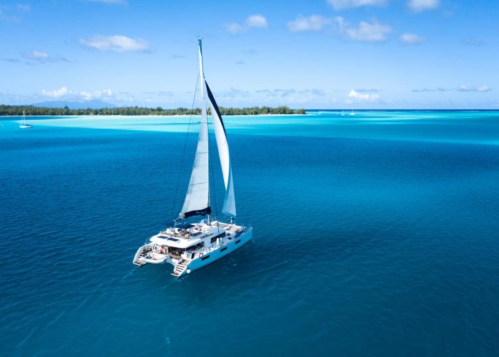 Croisière Dream Yacht Charter. Vue aérienne sur un catamaran Lagoon 620. Lagon et motu en arrière plan.