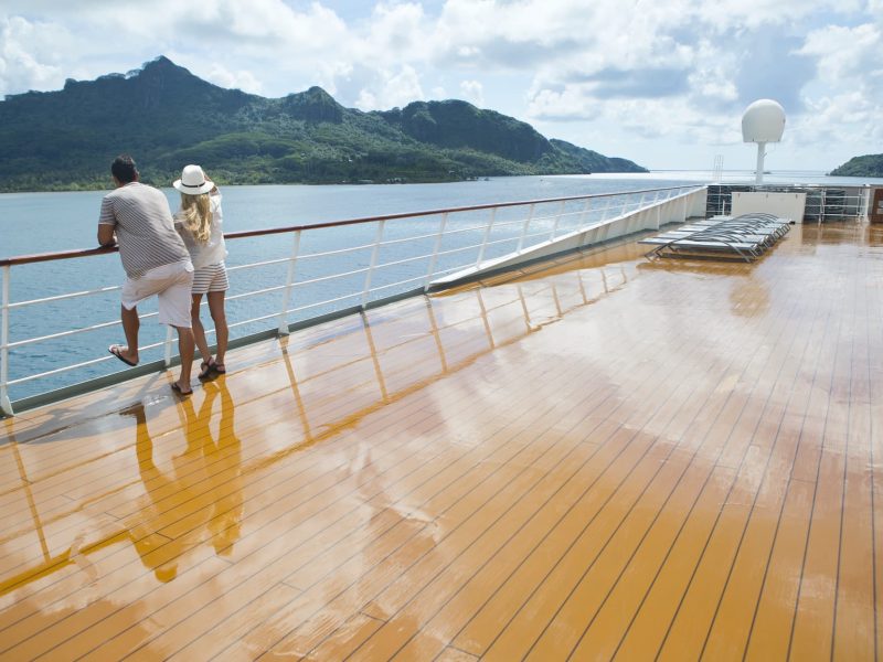 Croisière Paul Gauguin - Ponant. Couple regardant l'île de Huahine depuis le deck extérieur du paquebot Paul Gauguin.