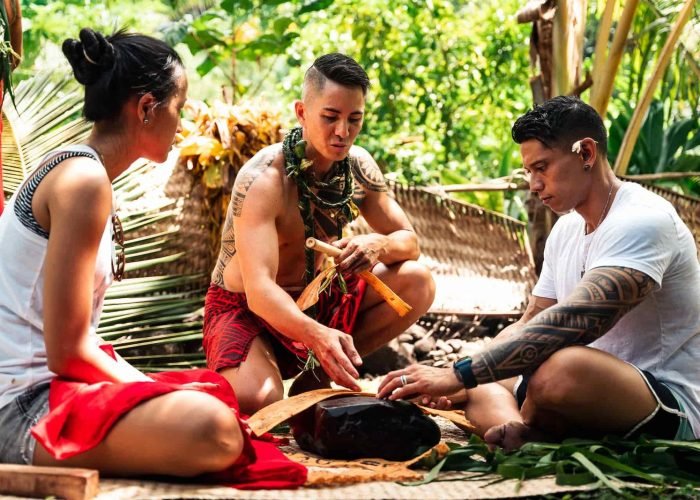 polynésien apprenant à un couple à faire du tapa