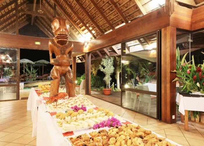 Hôtel Hanakee Lodge 3* à Hiva Oa – Buffet dans le restaurant de l'hôtel, avec tiki géant en bois.