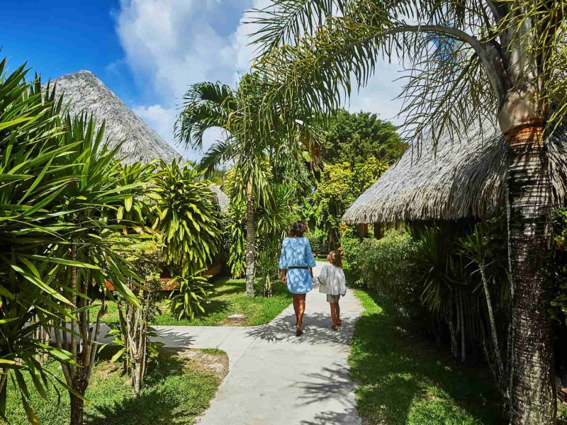 Hôtel Le Mahana 3* à Huahine - vue extérieur sur les jardins avec une mère et sa fille se promenant main dans main