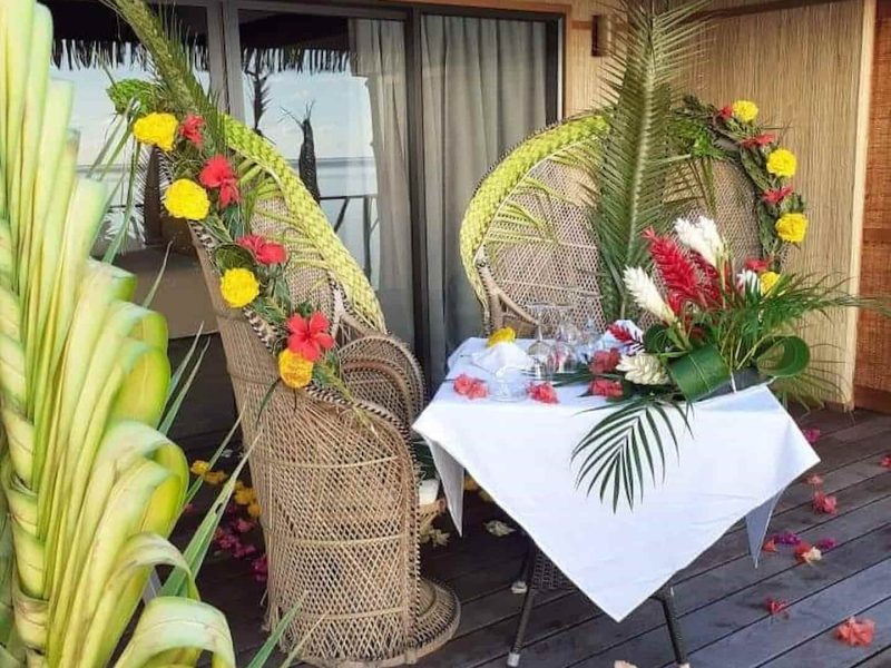 Hôtel Le Mahana 3* à Huahine. Vue de la terrasse d'un bungalow avec une table décorée pour un diner romantique. Chaises Pomare.