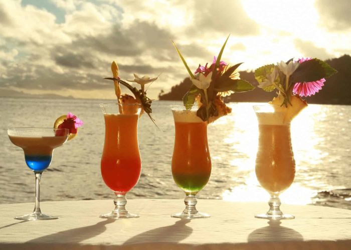 Hôtel Le Mahana 3* à Huahine. 4 cocktails tropicaux présentés face au lagon au coucher du soleil.