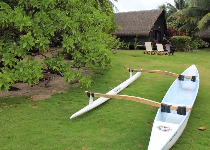 Pension Moana Lodge à Huahine. Pirogue à balancier dans le jardin et bungalow en arrière plan.