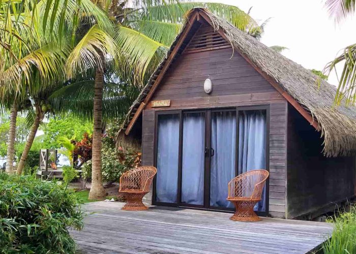 Pension Moana Lodge à Huahine. Vue de l'extérieur d'un bungalow traditionnel dans le jardin de la propriété.