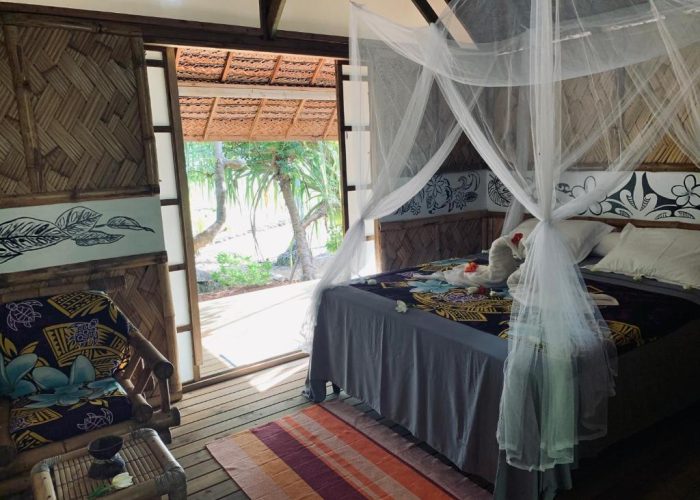 Pension Tupuna à Huahine. Vue de l'intérieur d'un bungalow jardin et son lit à baldaquin.