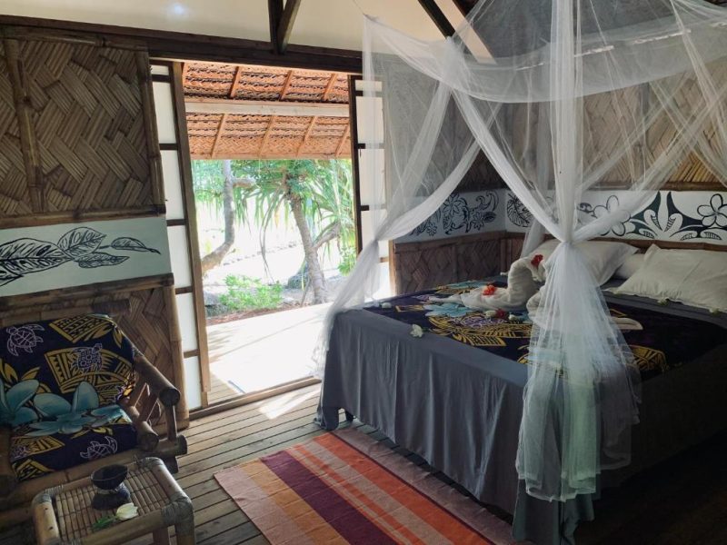 Pension Tupuna à Huahine. Vue de l'intérieur d'un bungalow jardin et son lit à baldaquin.