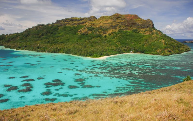 vue depuis une colline sur l'île montagneuse de Mangareva et son lagon turquoise avec des patates de corail en contre bas. Archipel des Gambier en Polynésie française