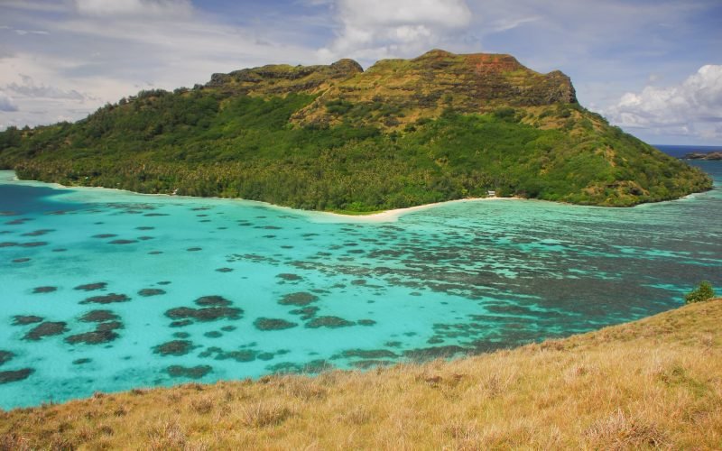 vue depuis une colline sur l'île montagneuse de Mangareva et son lagon turquoise avec des patates de corail en contre bas. Archipel des Gambier en Polynésie française