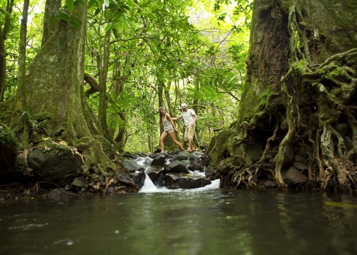 Couple traversant un ruisseau lors d'une randonnée à Moorea