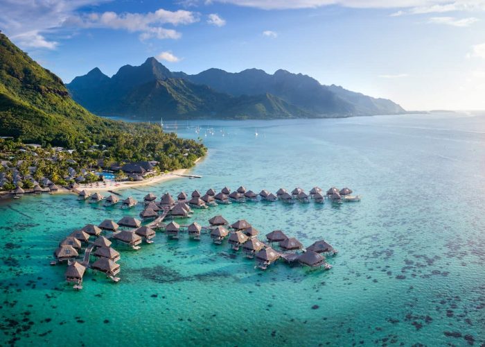 Hôtel Hilton Lagoon Resort & Spa 5* à Moorea. Vue aérienne générale sur l'hôtel, le lagon, et les bungalows sur pilotis. Montagnes de Moorea en arrière plan.