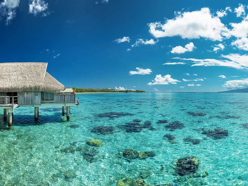 Hôtel Sofitel Kia Ora Beach Resort 5* à Moorea. Lagon turquoise, patates de corail, et bungalow sur pilotis "Horizon" sur la gauche.