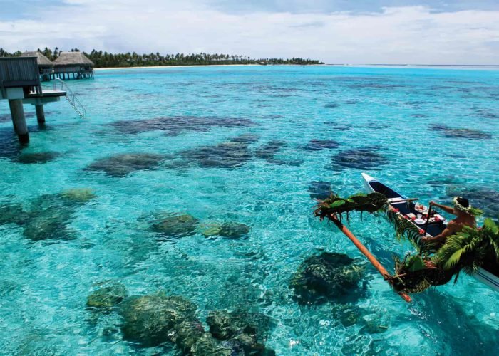 Hôtel Sofitel Kia Ora Moorea Beach Resort 5* - hommep olynésien apportant le petit déjeuner à un bungalow sur pilotis en pirogue traditionnelle.