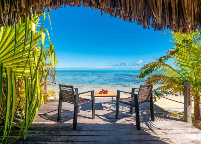 Pension Moorea Beach Lodge à Moorea. Terrasse extérieure d'un Bungalow "Honeymoon" avec vue sur le lagon turquoise et la plage de sable blanc.