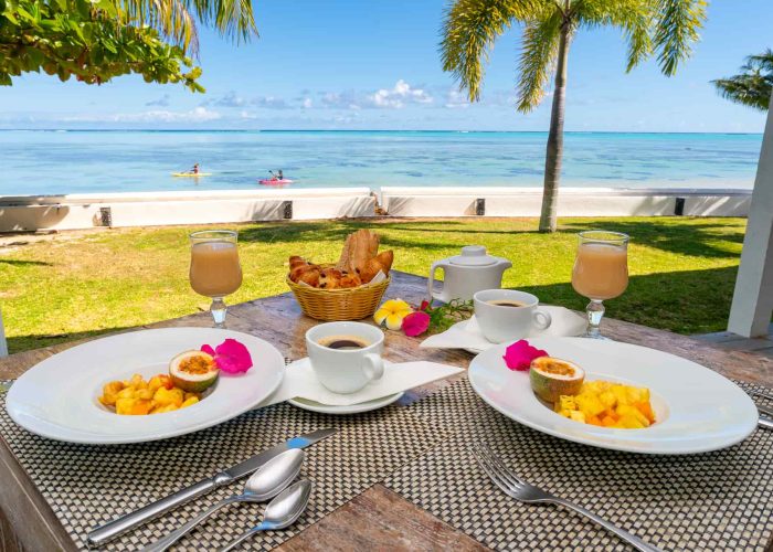 Pension Moorea Beach Lodge à Moorea. Petit déjeuner servit face au lagon. Lagon et deux kayaks en arrière plan.