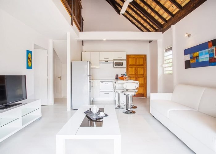 Résidence Moorea Sunset Beach. Intérieur d'un bungalow avec salon et coin cuisine.