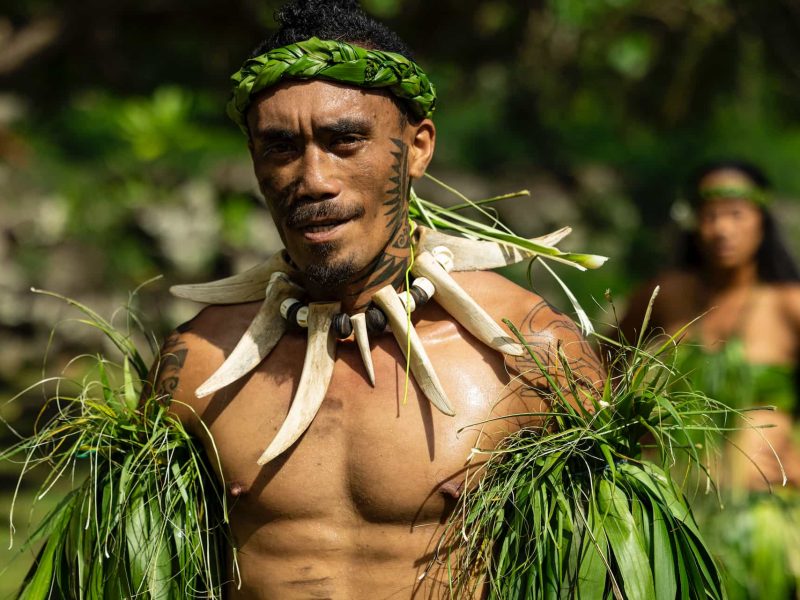 Marquisien tatoué au visage, habillé en tenu végétale et collier en défenses de cochon.