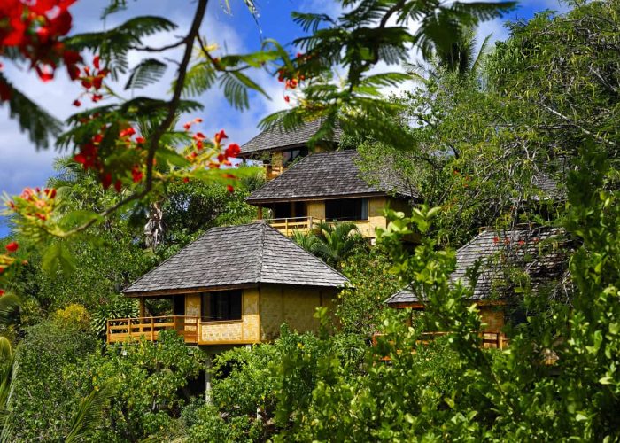 Hôtel Le Nuku Hiva by Pearl Resorts 3*. Vue extérieure sur les bungalows à flanc de colline, entourés de végétations.