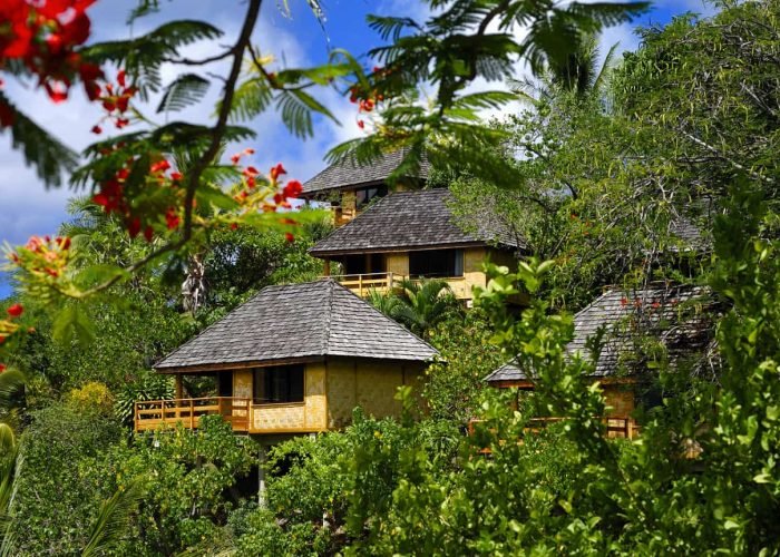Hôtel Le Nuku Hiva by Pearl Resorts 3*. Vue extérieure sur les bungalows à flanc de colline, entourés de végétations.
