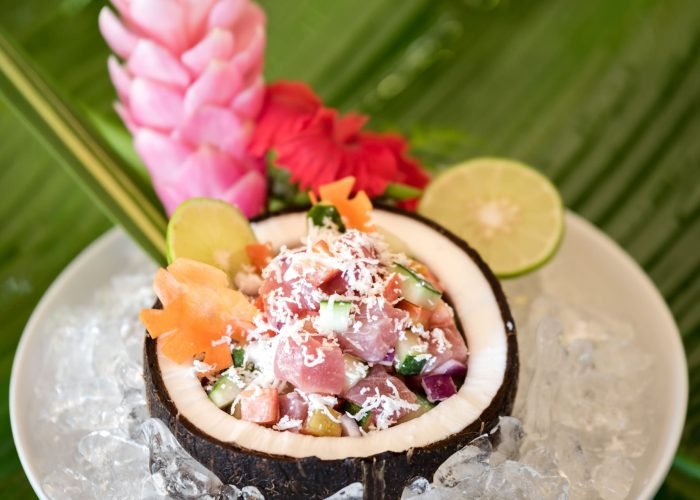 Zoom sur un plat traditionnel polynésien : poisson cru au lait de coco, servi dans une moitié de noix de coco.