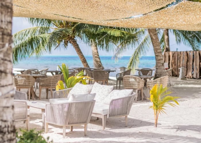 Hôtel Opoa Beach 3* à Raiatea - plage avec salon et lagon en arrière plan.