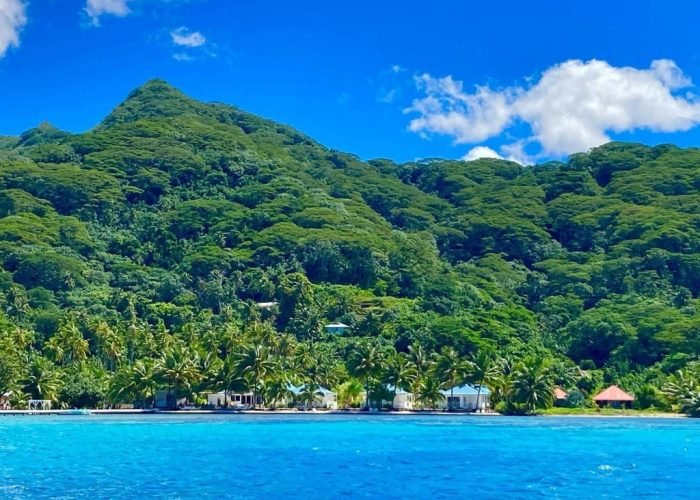 Hôtel Opoa Beach 3* à Raiatea - vue depuis le lagon sur l'hôtel. Montagne en arrière plan.