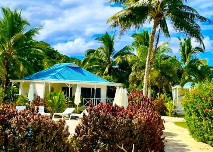 Hôtel Opoa Beach 3* à Raiatea - jardin avec palmier et bungalow en arrière plan.